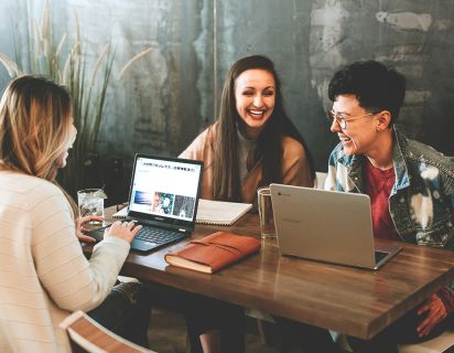 People laughing sitting at desk with laptops