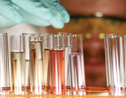 Man looking at vials of liquid in lab gear