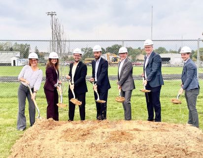 testape team lined up outside with shovels and dirt to break ground on new building